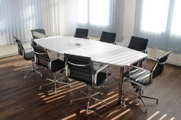 Ufficio con tavolo di lavoro attorniato da 8 sedie vuote